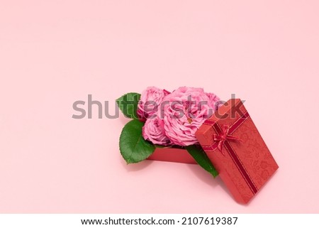 Beautiful pink roses in red gift box on pink background. Mother's day gift box with beautiful pink roses. Gift box with rose flowers bouquet