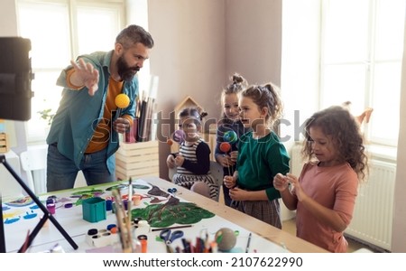Group of little kids working on project with teacher during creative art and craft class at school. Royalty-Free Stock Photo #2107622990