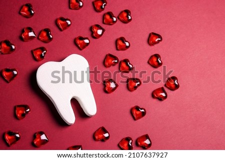 White teeth surrounded by red hearts on a red background. Dental Valentine card. Valentine's day concept.  