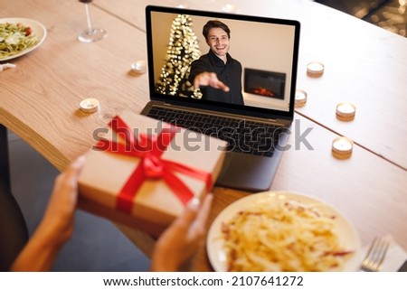 Long Distance Relationship. Loving millennial couple having online virtual date, man reaching hand to webcam in videochat with videoconferencing app window, woman showing him present box Royalty-Free Stock Photo #2107641272