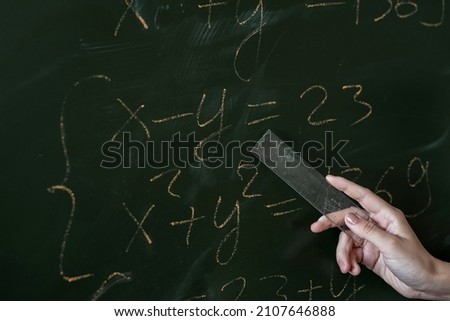 female hand writing math formulas on the classboard, close-up