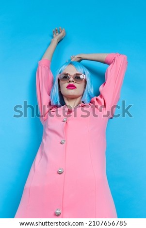 fashionable woman in sunglasses wears a blue wig makeup blue background