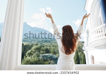 Portrait of young woman looks at a beautiful view from the balcony unaltered