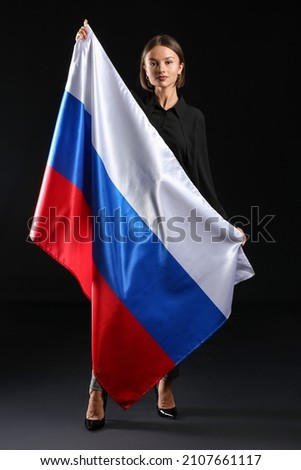 Beautiful young woman with flag of Russia on dark background