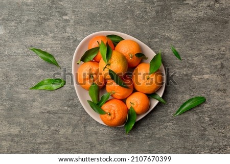 Fresh cutted clementines and whole mandarin over round plate on colored background. Food and drink ingredients preparing. healthy eating theme top view vith copy space.