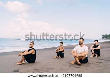 Concentrated male and female yogi training for feeling wellness and tranquility of mindfulness, calm group of hippies dressed in casual wear recreating on meditation practice yoga for health Royalty-Free Stock Photo #2107704965