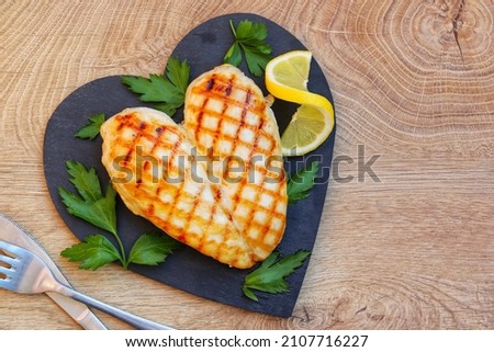 Heart shape grilled chicken breast on heart shape slate plate with wooden background.Love healthy food concept for Valentine's day.Top view.Copy space Royalty-Free Stock Photo #2107716227