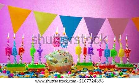 Birthday card with number 65 year. Happy birthday to six ten five year old. Candles burn with a festive cream cake. Greeting card