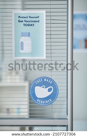 Vertical background image of Get Vaccinated sign and face mask sticker on glass door at vaccination clinic