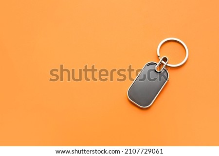 Stylish metallic keychain on orange background
