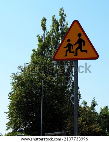 triangular sign with children on the background of the sky and trees. side view