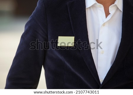 Blank identity tag hanging from a business man suit outdoors