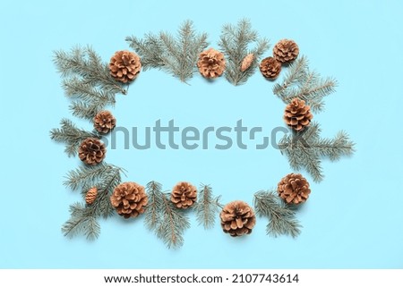 Frame made of fir branches and pine cones on color background