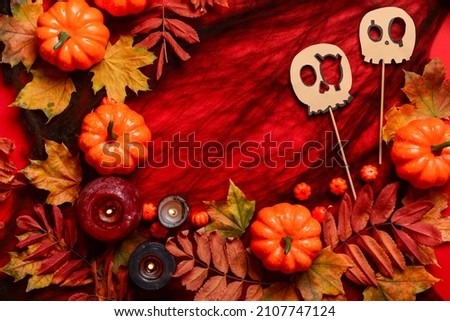 Pumpkins with burning candles and Halloween decor on red background