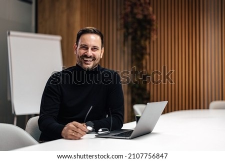 Picture of laughing adult man, exited about his new office in the company.