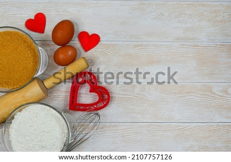 red festive ingrediens for cooking, valentines day eggs, rolling pin and whisk, cutter dish shape heart for baking cake flat lay.