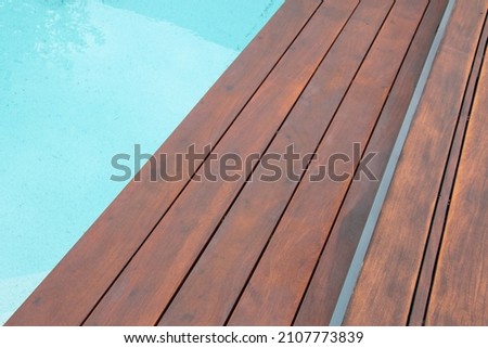 Detail of swimming pool coping and cover constructed by cumaru wood deck, hardwood decking texture next water Royalty-Free Stock Photo #2107773839