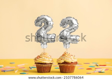 Tasty Birthday cupcakes with number 22 on color background Royalty-Free Stock Photo #2107786064
