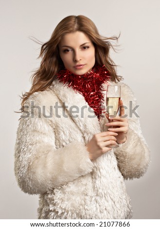 Young beautiful woman in white fur coat with glass of champagne on the white background