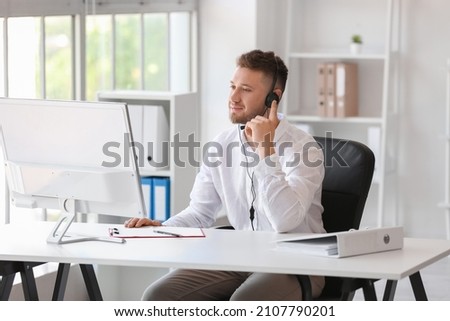 Handsome consultant of call center working at table in office Royalty-Free Stock Photo #2107790201