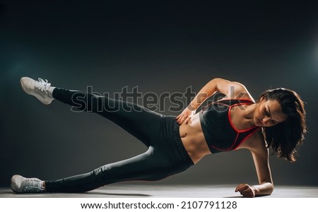 Fitness woman doing stretching workout. Full length shot of young woman on dark background. Stretching and motivation