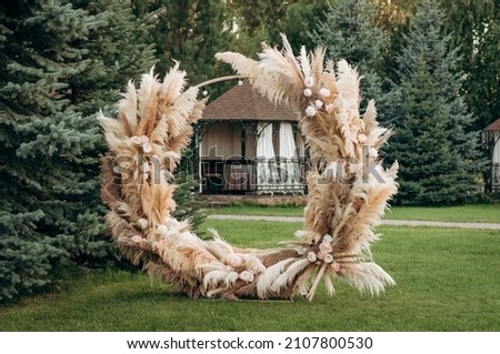 Wedding ceremony in the garden for the bride and groom. The arch is made of fresh flowers and dead wood, reeds. Outdoor wedding ceremony. Royalty-Free Stock Photo #2107800530