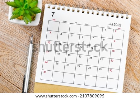 The July 2022 desk calendar with pen on wooden table. Royalty-Free Stock Photo #2107809095