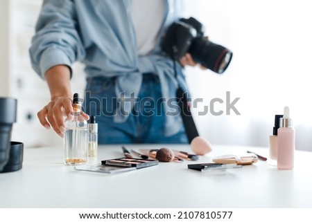 Object Photography. Unrecognizable Photographer Lady Putting Cosmetic Products On Table Making Composition And Taking Photo Of Makeup Background, Holding Camera Indoor. Selective Focus, Cropped