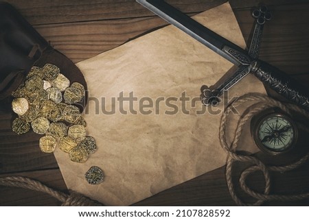 Travel or adventure flat lay background with copy space. Ancient gold coins,compass,rope and dagger on the old table.