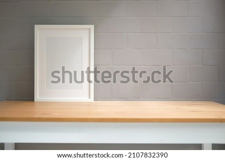 Empty picture frame on wooden table with brick wall. Copy space for your advertising text.