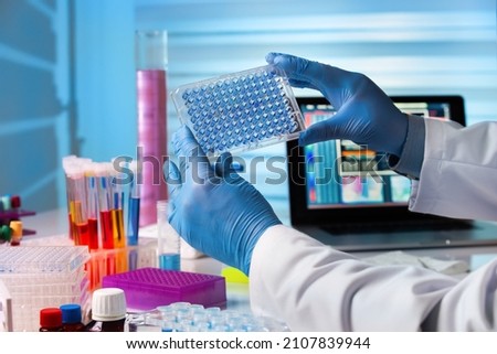 Scientist working in laboratory with samples in micro plate. Researcher in lab holding a 96 well plate with biological samples for analysis Royalty-Free Stock Photo #2107839944