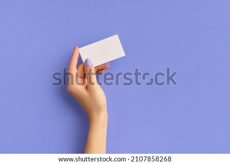 Womans hand holding business card on purple background. Business work template mockup. Empty greeting card with space for text