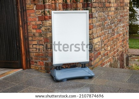 Empty signboard in front of an old church building, blank white sign, no text
