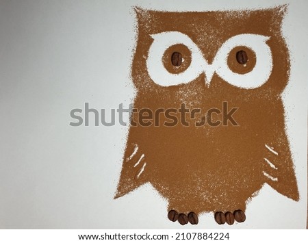 Light background with a silhouette of an owl from instant coffee with coffee beans. Space for copy.