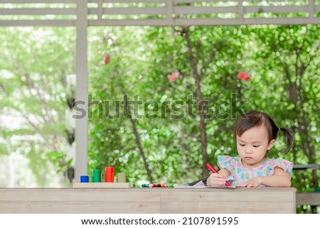 Little asian girl coloring cartoons on coloring book at home. Coloring Book Education Talent Concept. Copy space.
