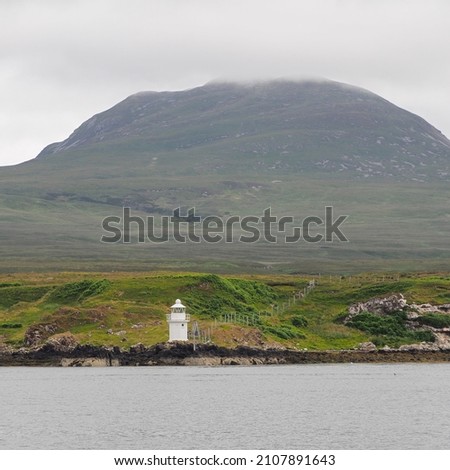 Carragh an t-Sruith lighthouse in the Sound of Islay near Feolin, Jura sits under the mountain shrouded in cloud, Hebrides, Scotland, UK