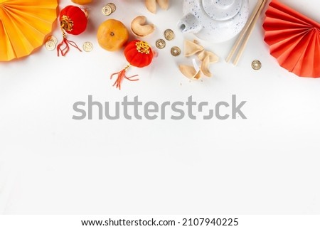 Chinese new year background. Red and golden yellow flatlay with traditional Chinese new year decor, envelopes with wishes, gold coins, fans, Chinese lanterns, oranges and tea