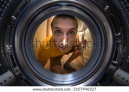 The man opens the washing machine. wide angle Royalty-Free Stock Photo #2107940327