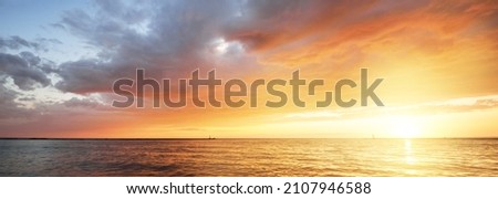 Baltic sea at sunset. Dramatic sky with glowing golden pink clouds, reflections in the water. Lighthouse. Setting sun. Epic seascape. Abstract natural pattern, texture, background, concept image Royalty-Free Stock Photo #2107946588