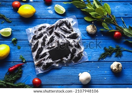 Frozen mussels in vacuum transparent packaging with taste on a textured wooden background next to vegetables, citrus fruits and herbs