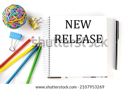 Notebook ,pencils,pen and rubber band with text NEW RELEASE on white background