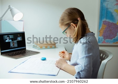 Cute little schoolgirl answering at virtual online lesson