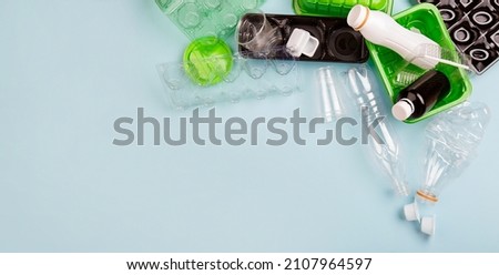 Separate collection of plastic garbage. PET stuff for recycle on blue background. Eco friendly concept. Recyclable plastic waste: aggs, candy box, bottle, meat container. Kind of polyethylene plastic  Royalty-Free Stock Photo #2107964597