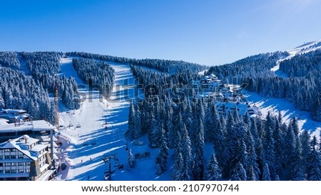 Drone view at slope on ski resort. Forest and ski slope from air. Winter landscape from a drone. Snowy landscape on ski resort. Aerial photography