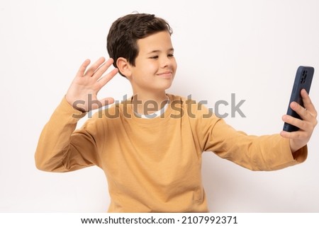 Caucasian boy in casual clothing using smartphone isolated over white background.