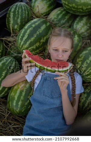 The girl is sitting on watermelons in the car. Eating a watermelon. Summer. Autumn. Harvesting. Environmentally friendly products. Agriculture. Farming.