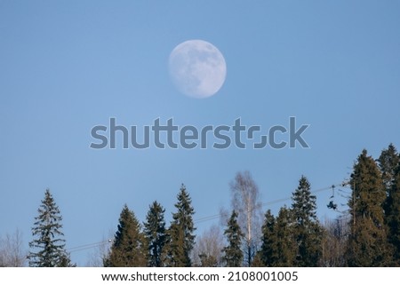 Full moon ski chairs winter background. Ski lift under the forest