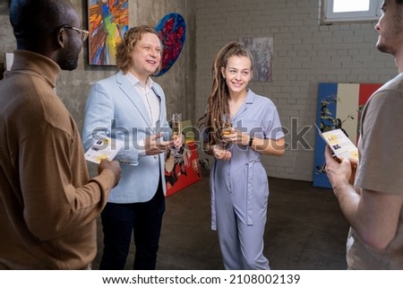 Group of happy intercultural guests of art gallery having champagne during discussion of modern art Royalty-Free Stock Photo #2108002139