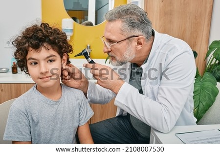 Otoscopy and hearing check-up for boy at audiology office. Audiologist examining child's ear with otoscope Royalty-Free Stock Photo #2108007530