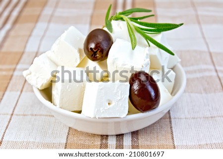 Feta cheese, olives, rosemary in a white bowl on a background of brown tablecloth Royalty-Free Stock Photo #210801697